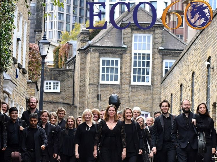 The English Chamber Orchestra walk along a street in black clothes towards the camera