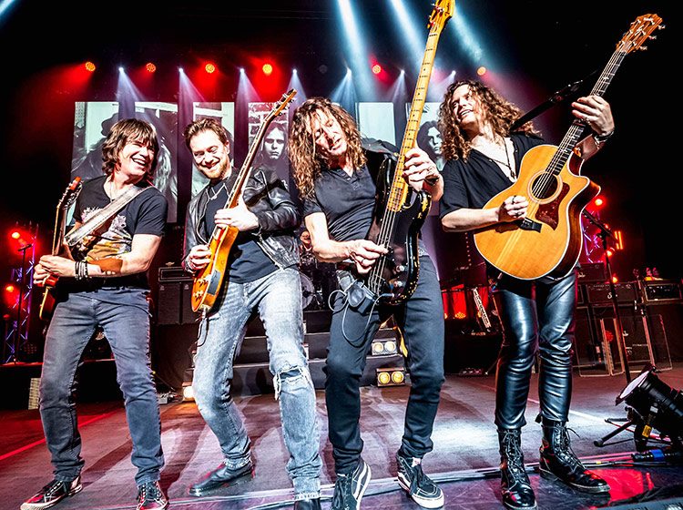 Four musicians in a line rocking out on their guitars